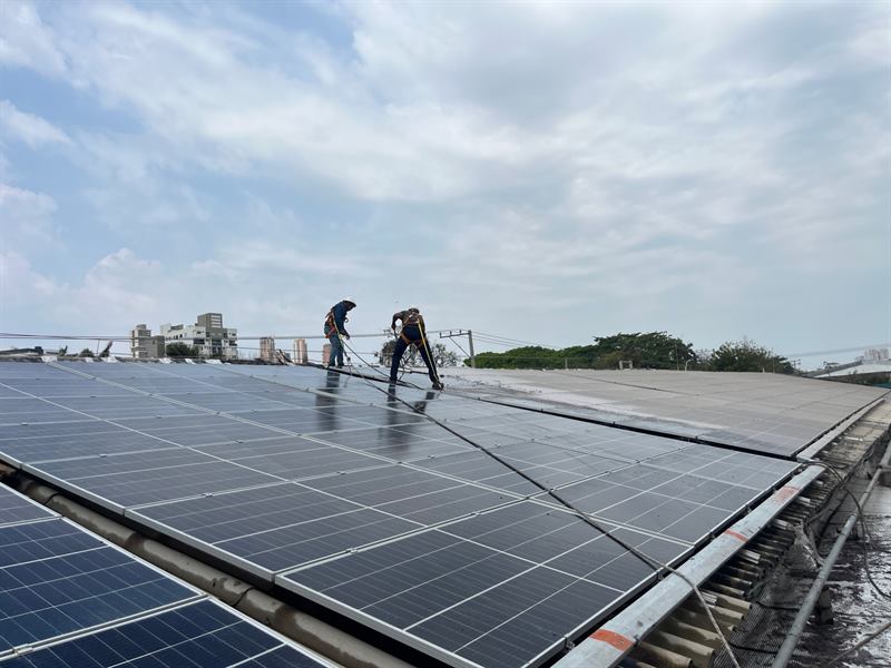 Dos técnicos con arnés limpiando módulos solares